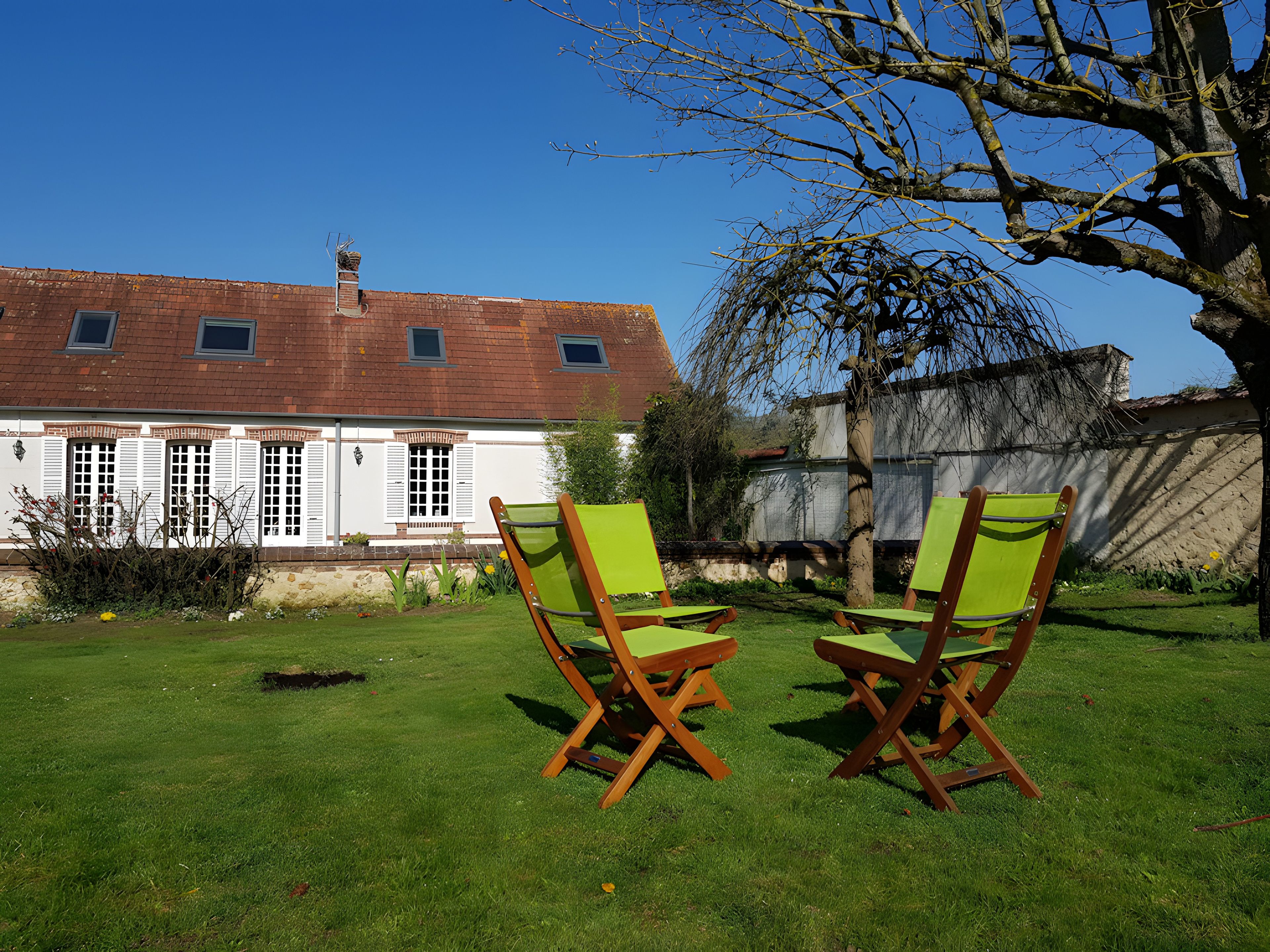 A grassy outdoor area with two wooden chairs and a building with a red roof in the background.