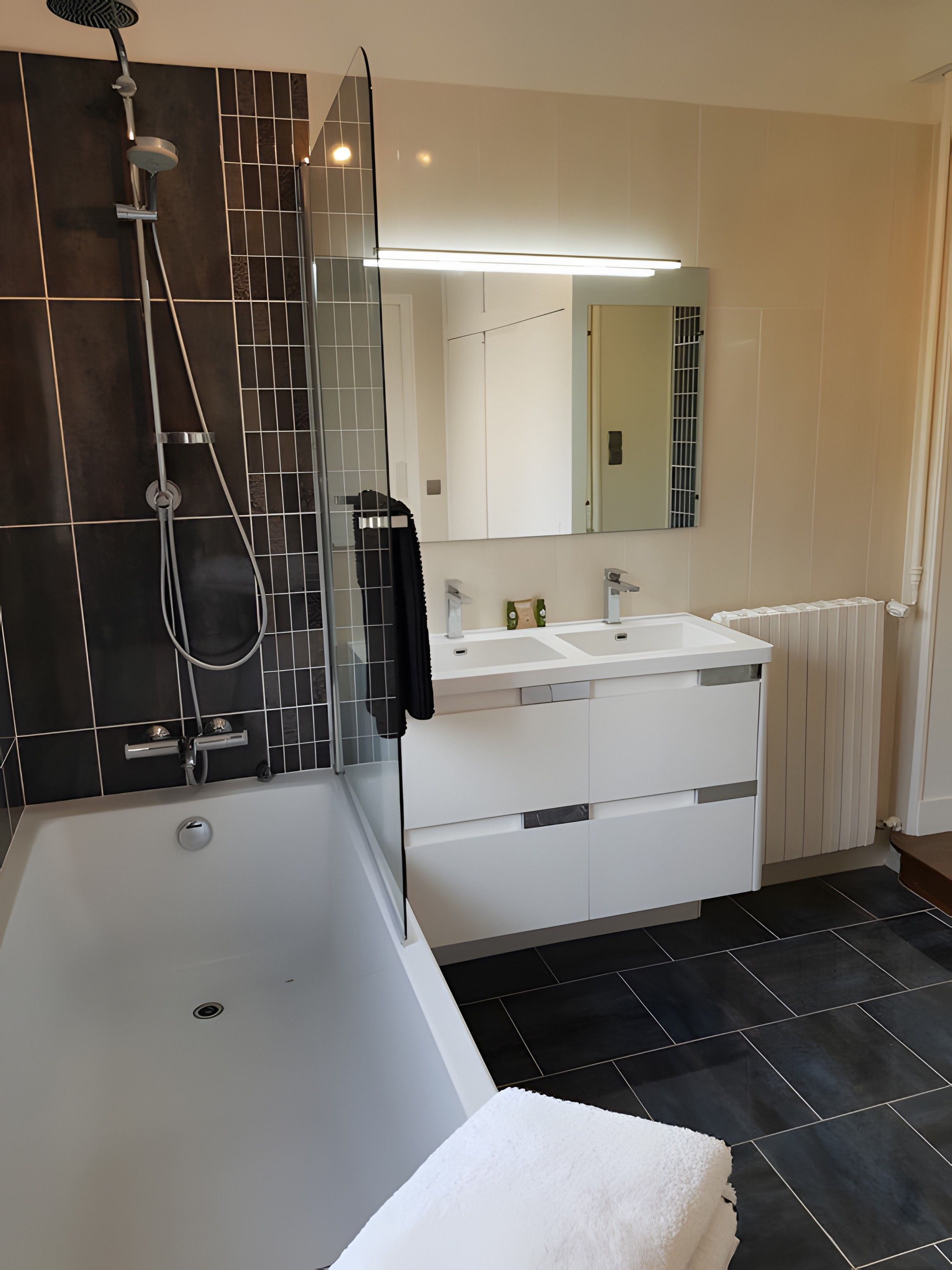 Un baño moderno con una bañera, dos lavabos, una ducha y un espejo grande.