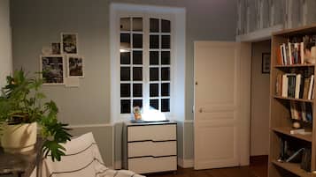 Een kamer met een bed, een bureau, een boekenkast, een raam en een deur.