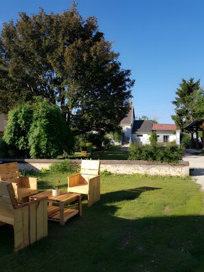 An outdoor seating area with wooden furniture, a stone wall, and a large tree in the background. - Guest Room "Chambre Verte – 1st Floor" with Shared Garden and Wi-Fi (Saint-Germain-sur-Avre)