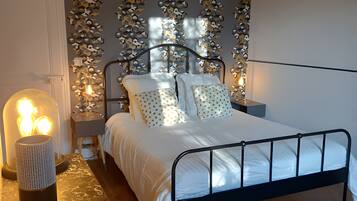 A bedroom with a metal bed frame, white bedding, a patterned wall, and a bedside lamp.