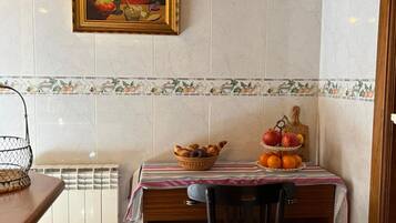 Un comedor con una mesa lista para dos personas, un radiador y un cuadro en la pared.