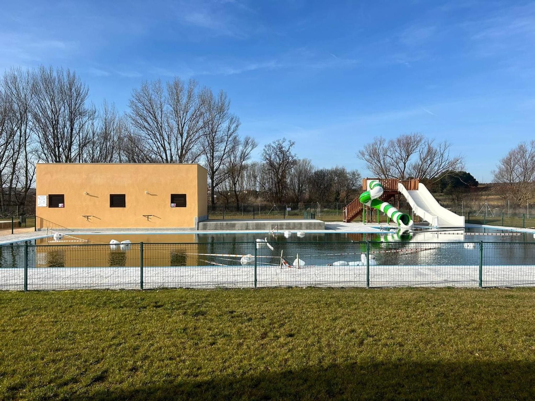 En swimmingpool med en vattenrutschkana och en byggnad med fönster.