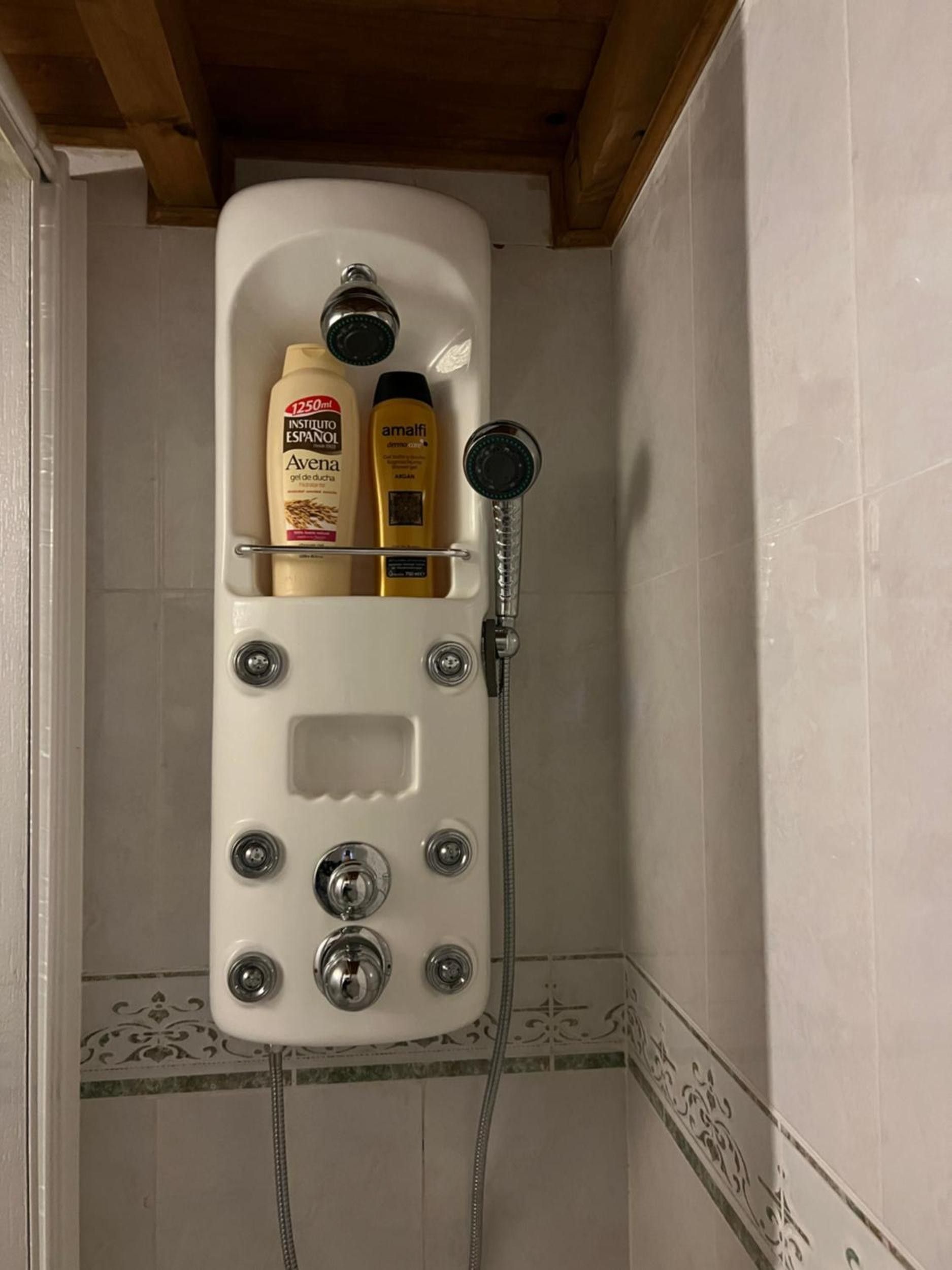 Une cabine de douche dotée d’une étagère intégrée pour ranger les articles de toilette.