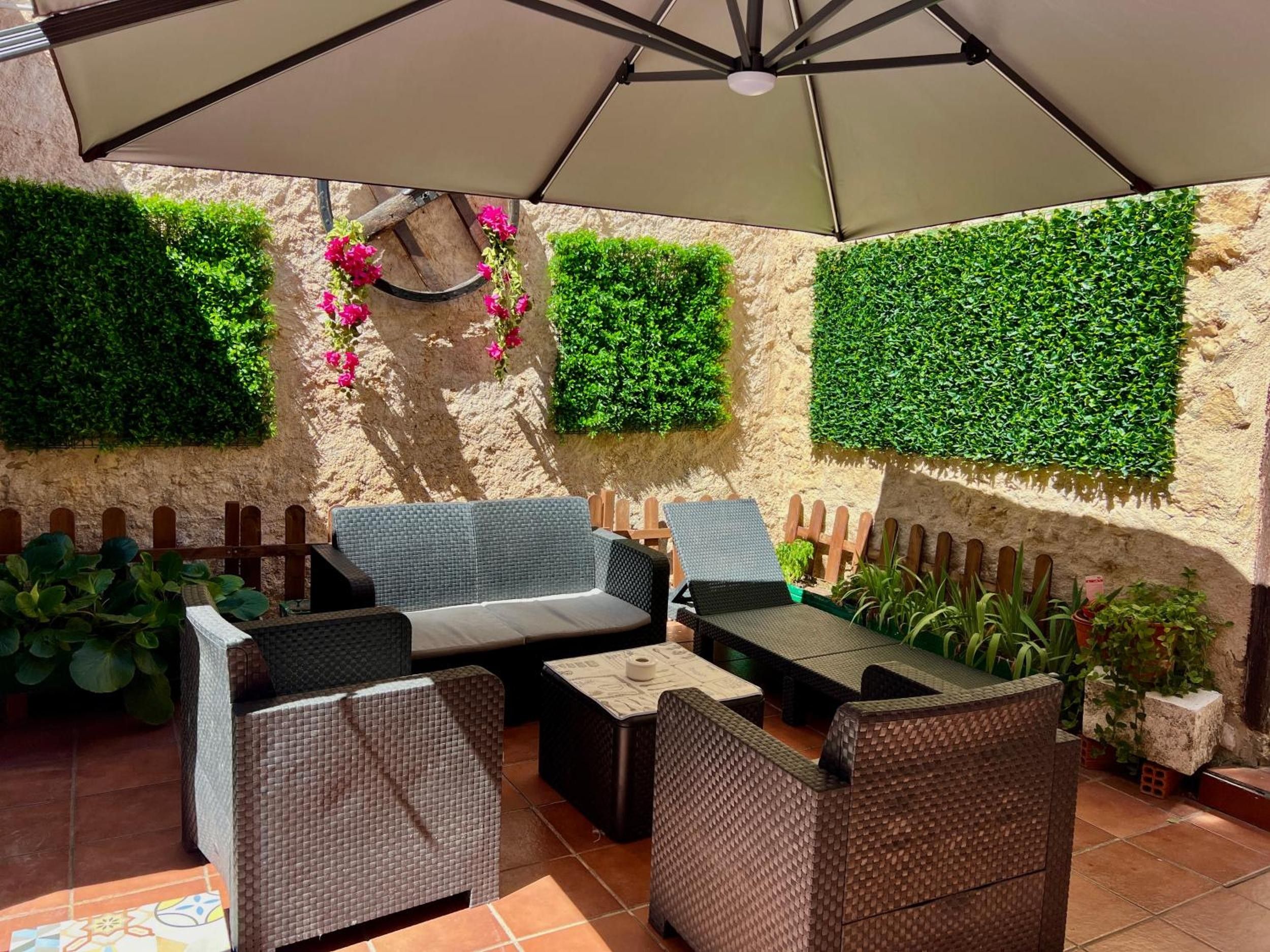 Un espace extérieur aménagé avec des meubles en osier, une pergola et des éléments décoratifs végétaux sur les murs.
