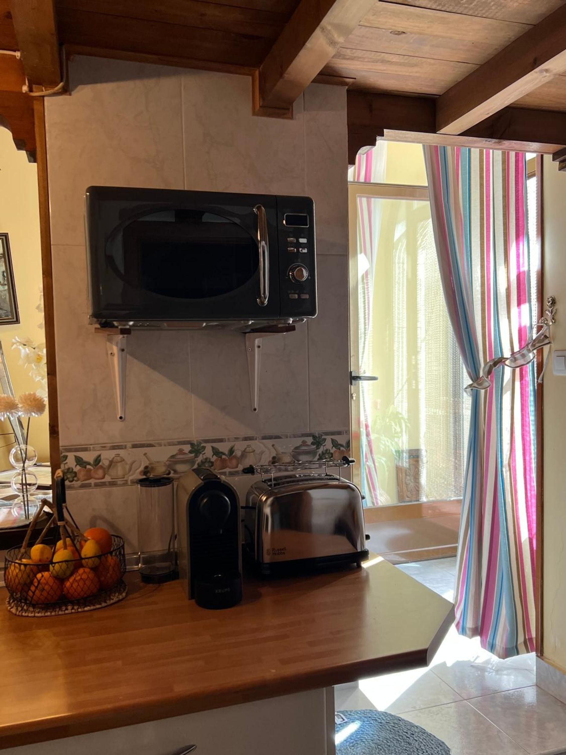 A kitchen with a microwave, toaster, and fruit basket.