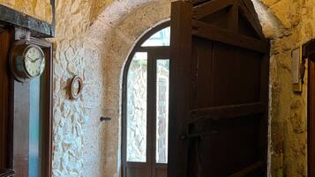 A rustic interior with a stone wall, wooden door, and a tiled floor.
