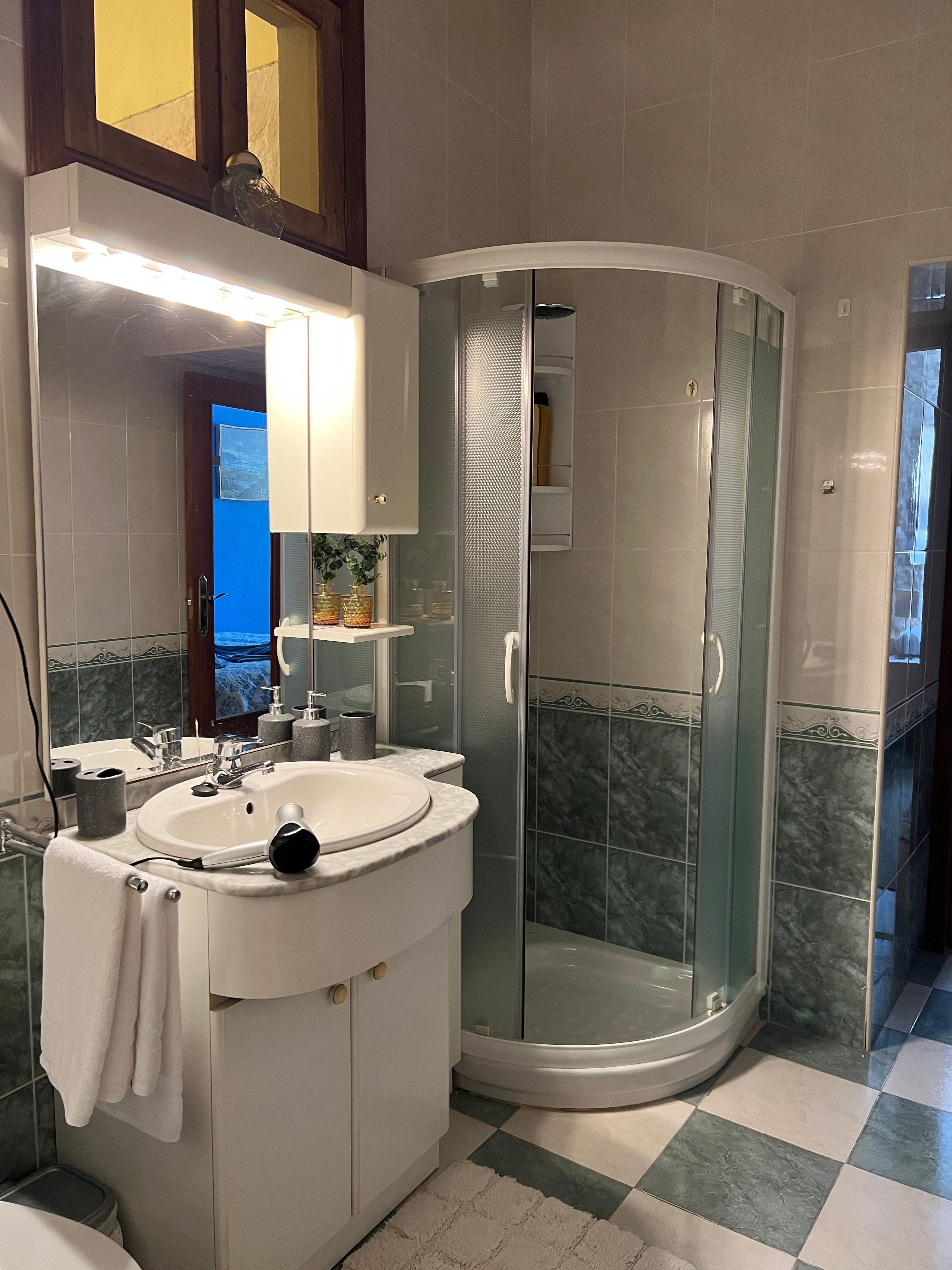 A bathroom with a round sink, a glass shower enclosure, and a mirror above the sink.