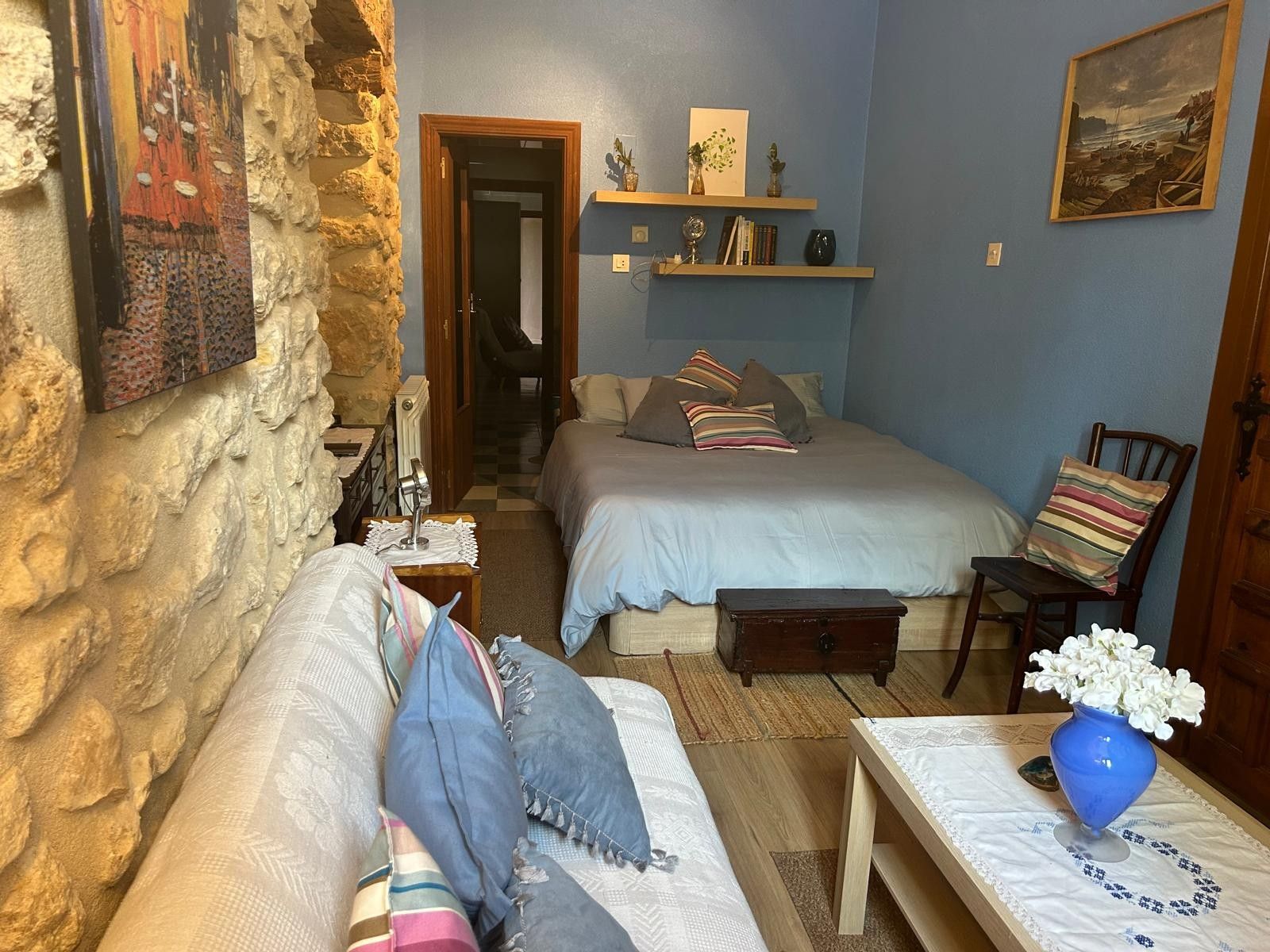 Un dormitorio acogedor con dos camas, un tocador de madera, una silla y una mesita de noche con un jarrón.