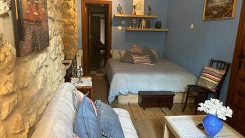 Un dormitorio acogedor con dos camas, un tocador de madera, una silla y una mesita de noche con un jarrón.