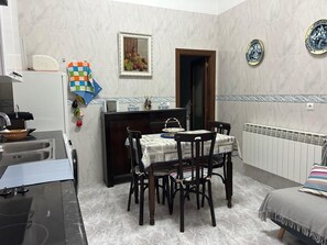 A compact kitchen with a dining area, a refrigerator, a sink, and a table set for two.