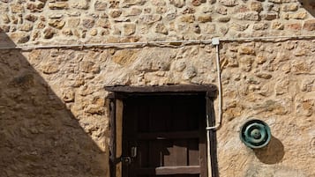 A stone building with a wooden door, outdoor seating, and a potted plant.