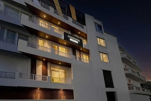 A multi-story hotel with balconies, a sign indicating it's a temporary residence, and a night sky. - Townhouse Railway Road Katra Formerly (Katra)