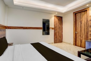 A hotel room with a bed, a desk, a mirror, and wooden doors. - Townhouse Railway Road Katra Formerly (Katra)