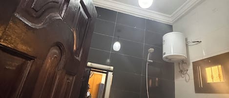Casa de banho com lavatório branco, chuveiro e espelho.