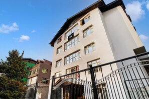 A multi-story building with a gated entrance, large windows, and a clear sky. - Super Townhouse Rajbagh Formerly Hotel (Srinagar)