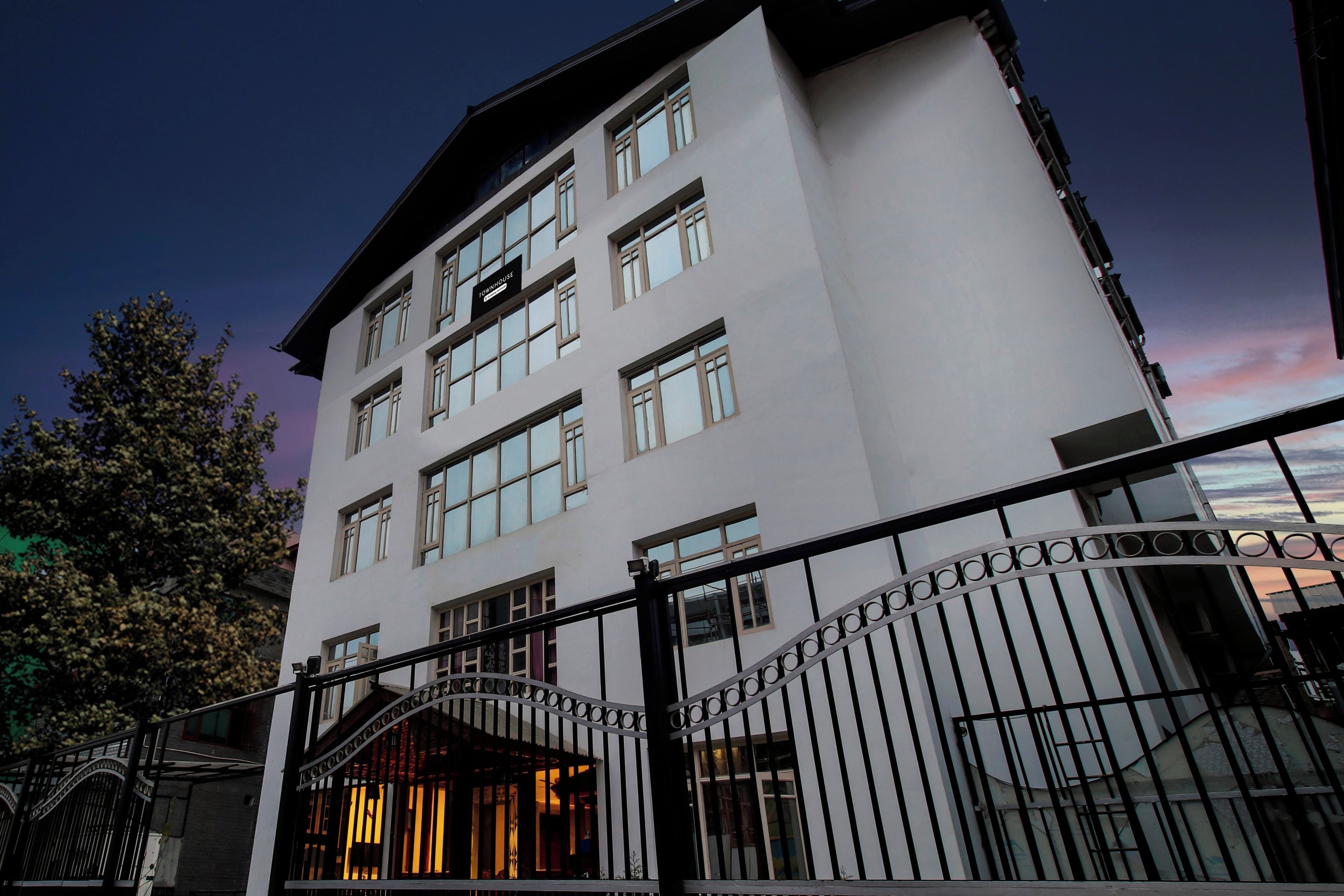 A multi-story hotel with a modern facade, large windows, and a gated entrance.