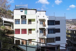 Un edificio de varios pisos con balcones y ventanas, ubicado en una ladera.