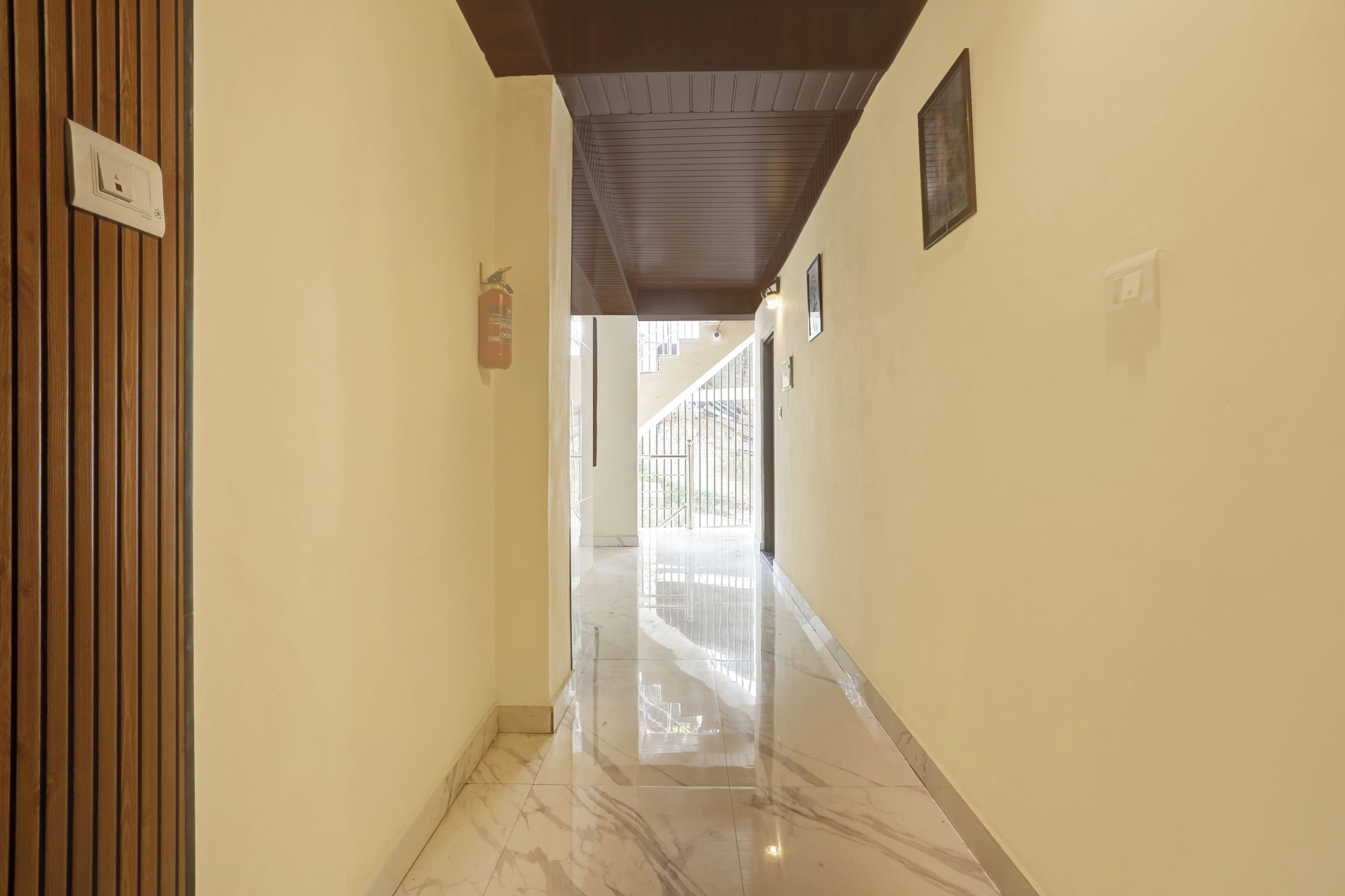 Um corredor com porta de madeira, extintor de incêndio e interruptor na parede.