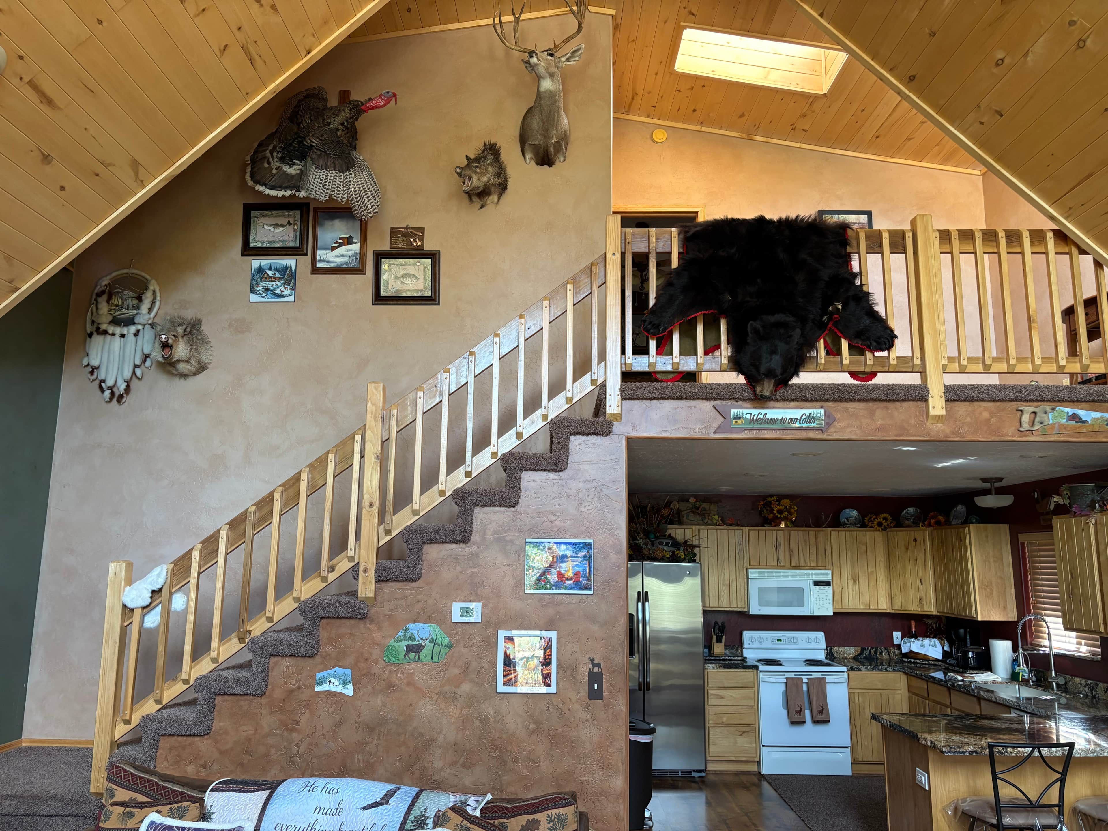 A multi-level cabin with a wooden staircase, a kitchen area, and various wall decorations including mounted animal heads.