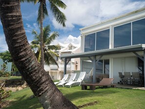 A modern house with a covered patio area, outdoor seating, and a view of the surrounding landscape.