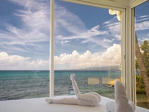 A room with a large window overlooking a body of water and a clear sky.