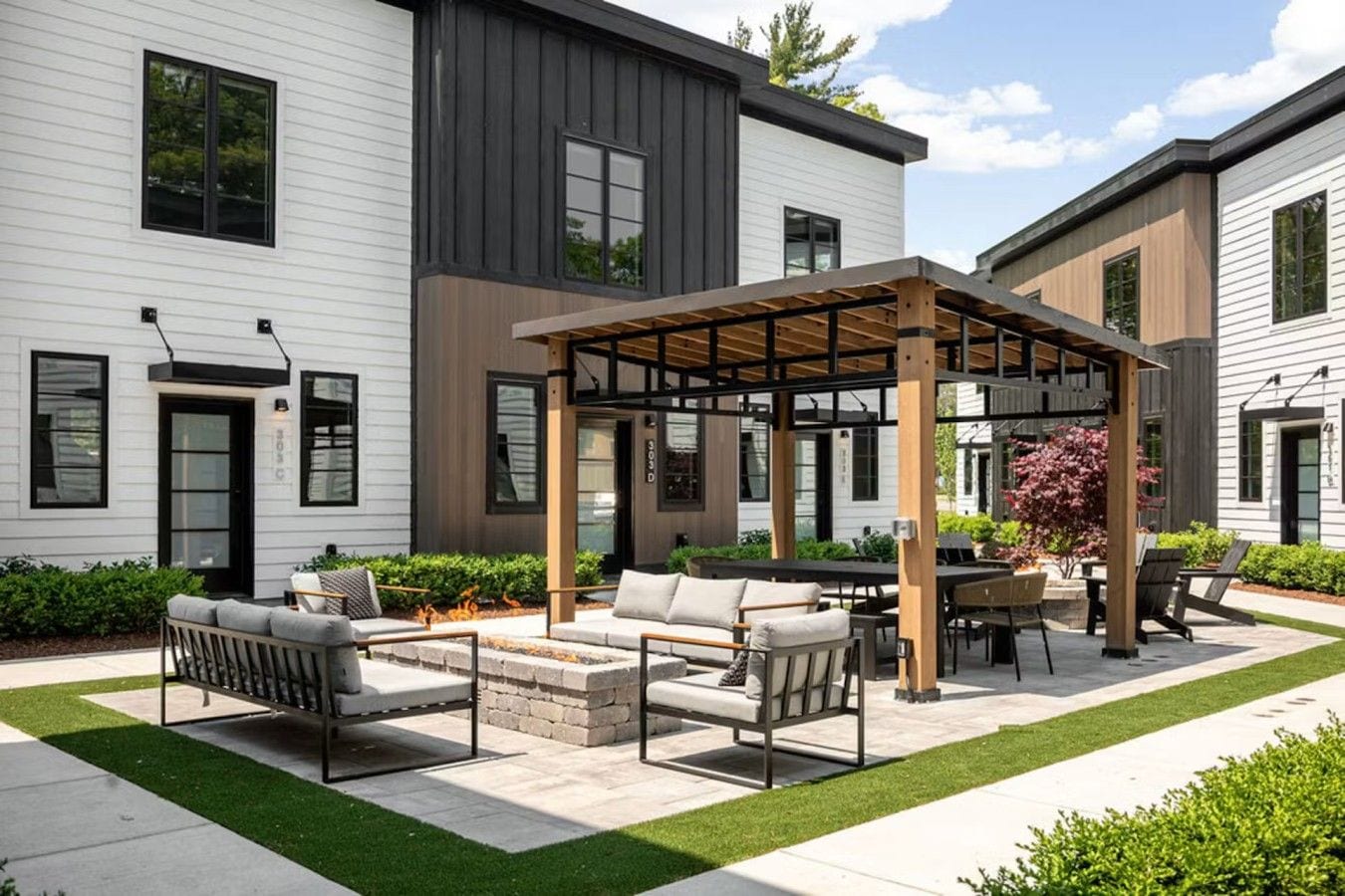 A modern outdoor patio with a pergola, outdoor seating, and a well-maintained lawn.