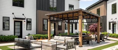 A modern outdoor patio with a pergola, outdoor seating, and a well-maintained lawn.