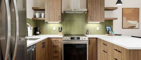 Eine moderne Küche mit Holzschränken, einem Edelstahlkühlschrank und einem Einbauofen.