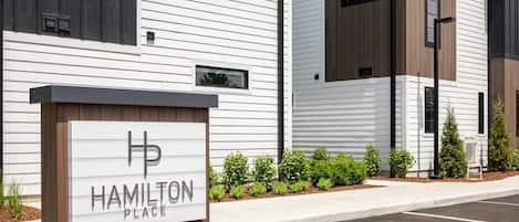A modern building with a sign reading 'Hamilton Place' and a parking lot in front.