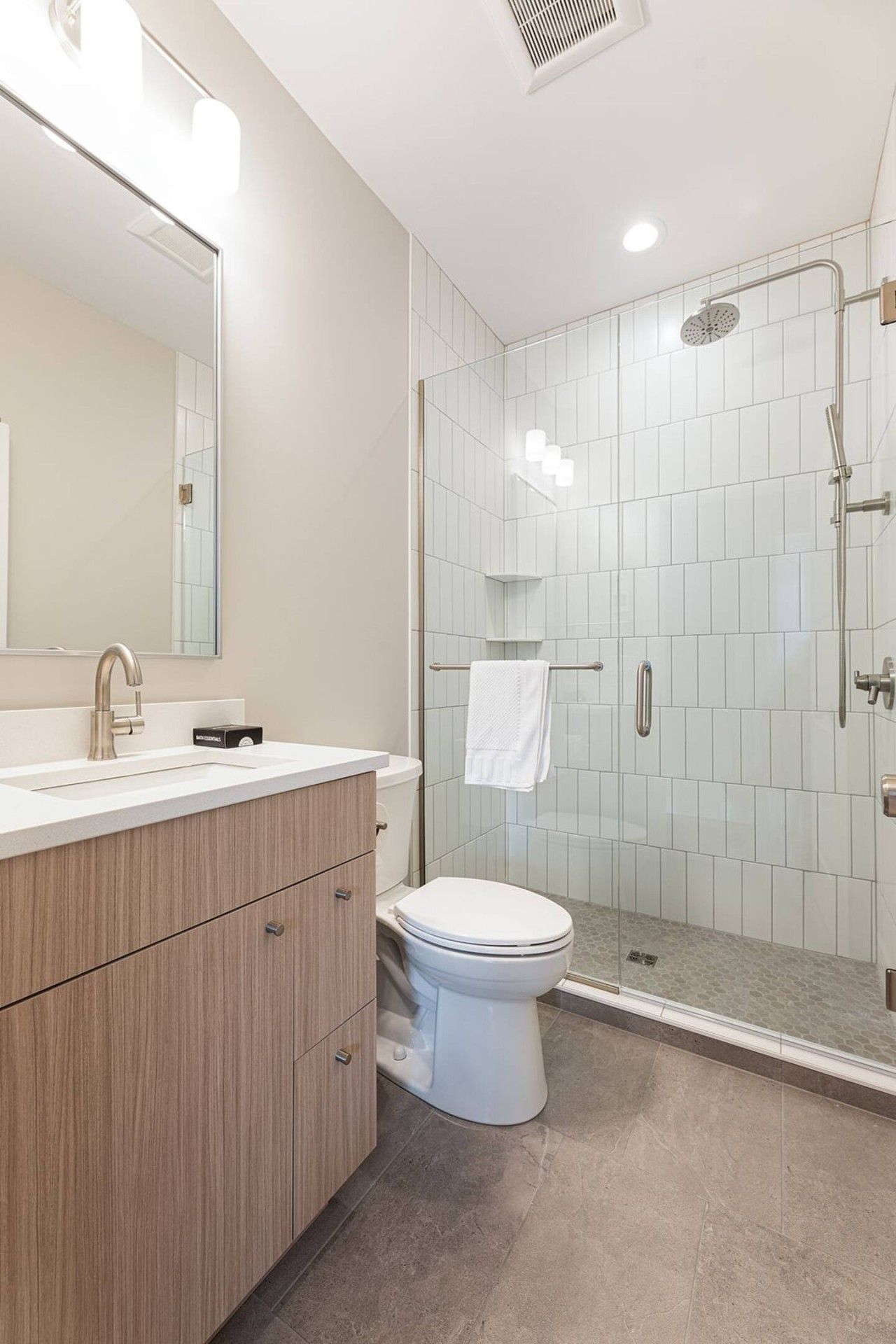 Une salle de bain moderne avec une douche à parois de verre, des toilettes et un meuble-lavabo avec un miroir.