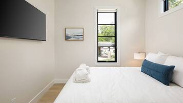 Une chambre d’hôtel avec un lit, une fenêtre donnant sur un paysage agréable, un tableau accroché au mur et une serviette sur le sol.