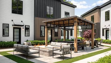 Un patio moderno al aire libre con pérgola, mobiliario exterior y un césped bien cuidado.
