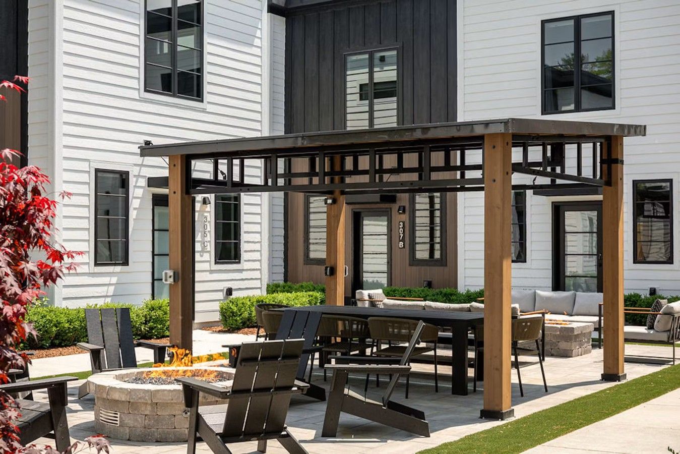 An outdoor patio area with a pergola, seating, and a fire pit.