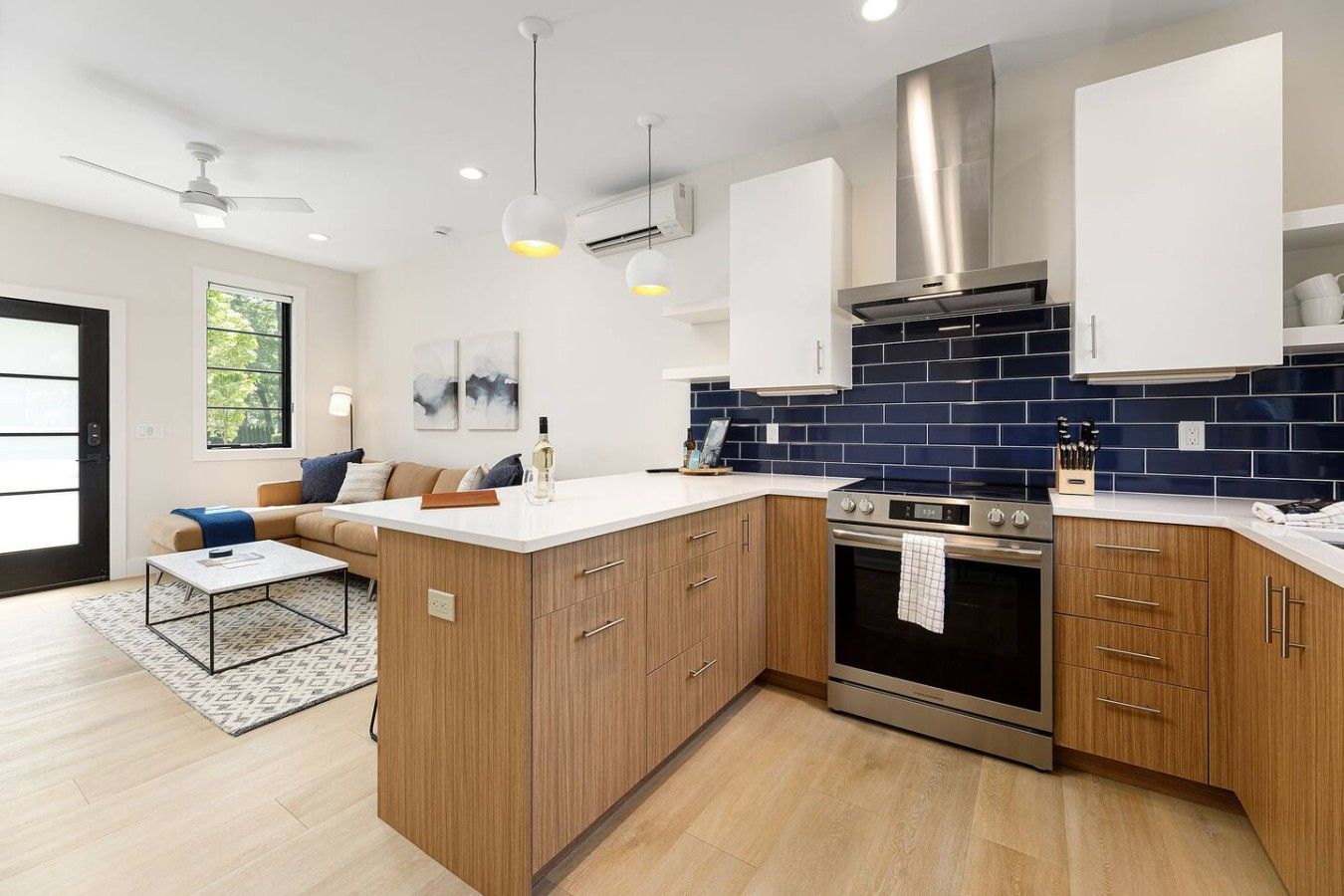 Una cucina moderna con mobili in legno, forno in acciaio inossidabile e zoccolo a parete rivestito di piastrelle blu.