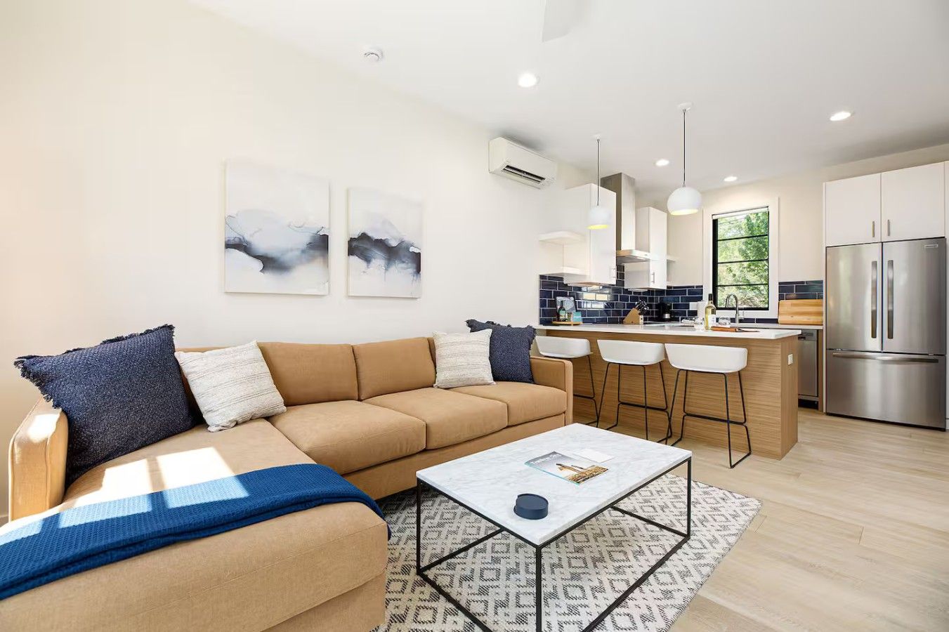 Een moderne woonkamer met een bank, salontafel en barstoelen.