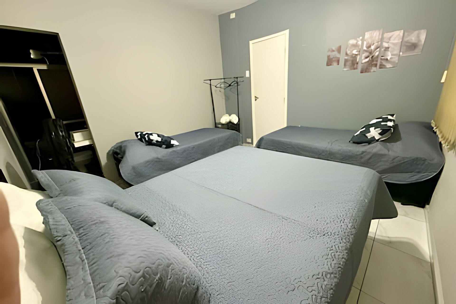 A room with two beds, a wardrobe, and a mirror.