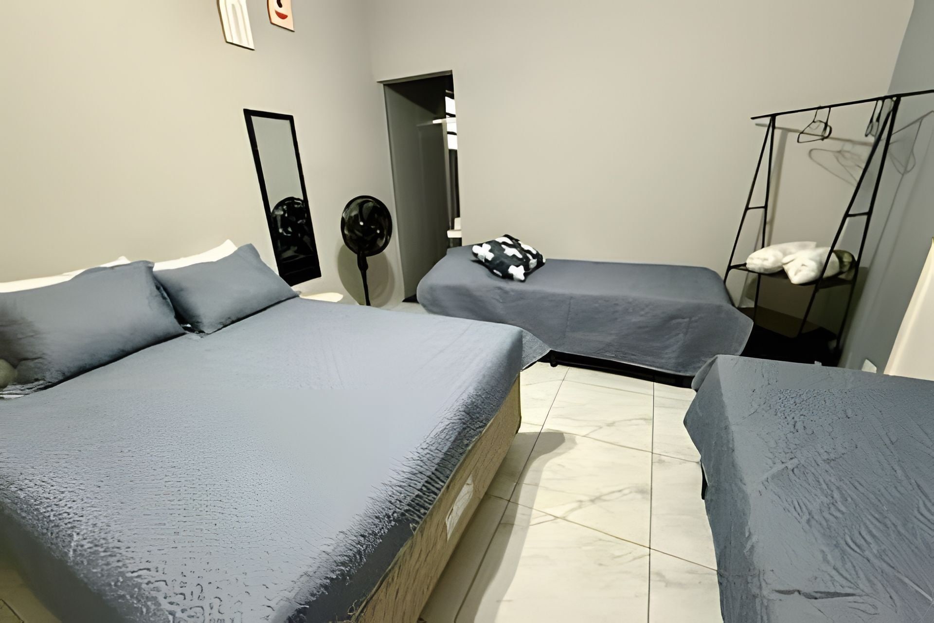 A room with two beds, a mirror, a fan, and a hanging chair.