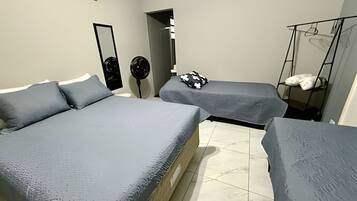 A room with two beds, a mirror, a fan, and a hanging chair.