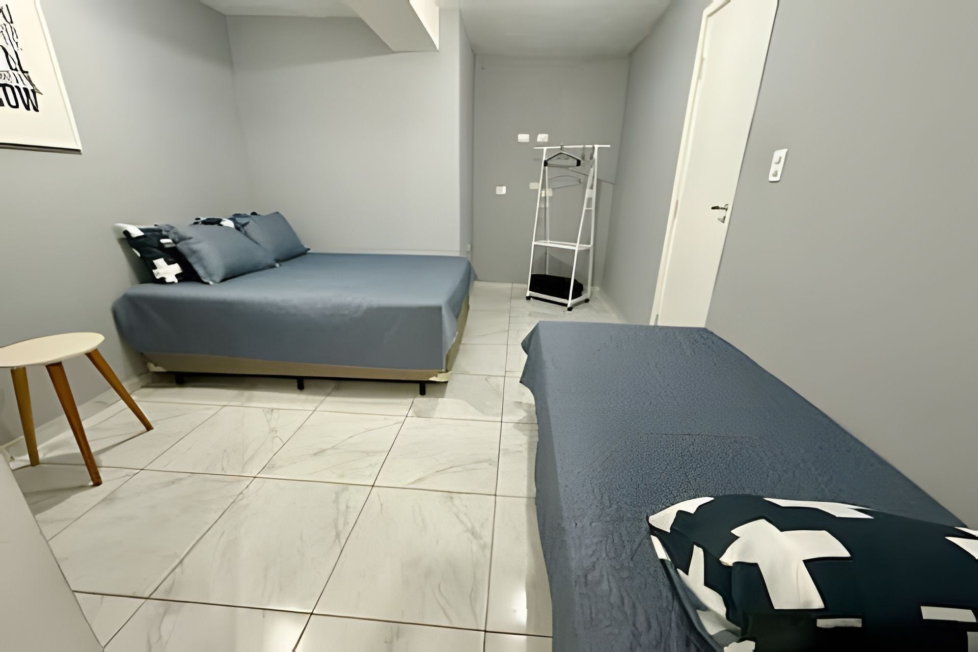A small, modern bedroom with a bed, a chair, and a wardrobe.
