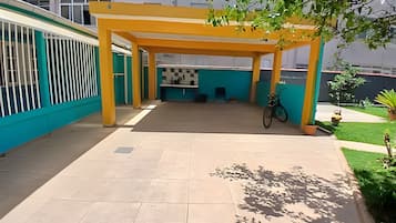 A covered outdoor area with a tiled floor, a bicycle, and a small garden with a plant and a fire hydrant.