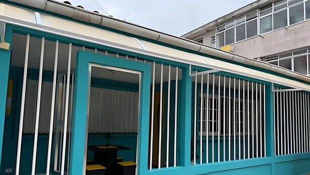 Um edifício com paredes verde-água e janelas emolduradas por branco.