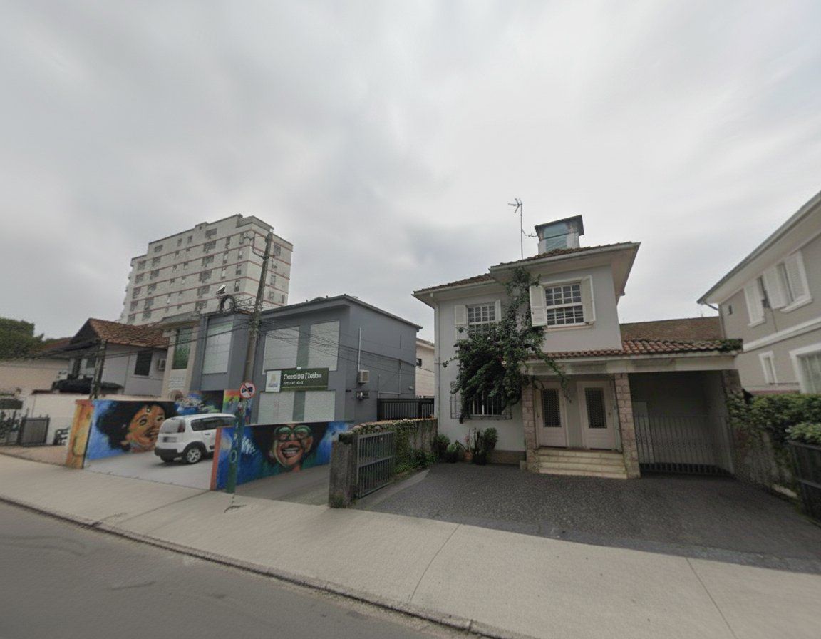 Eine Wohnstraße mit einem weißen Auto vor einem Haus mit einem Ziegeldach und einem kleinen Garten.