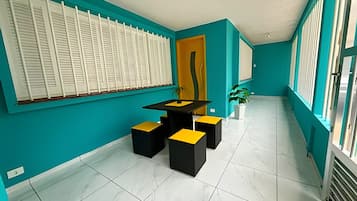 Un interior moderno con paredes color turquesa, una mesa negra y amarilla, y una planta en maceta.