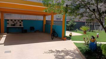 An outdoor patio area with a covered seating area, a bicycle, and a small garden with plants and a statue.