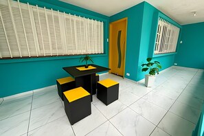 Una habitación moderna con paredes verde azulado, una mesa negra y amarilla, y una planta en maceta.