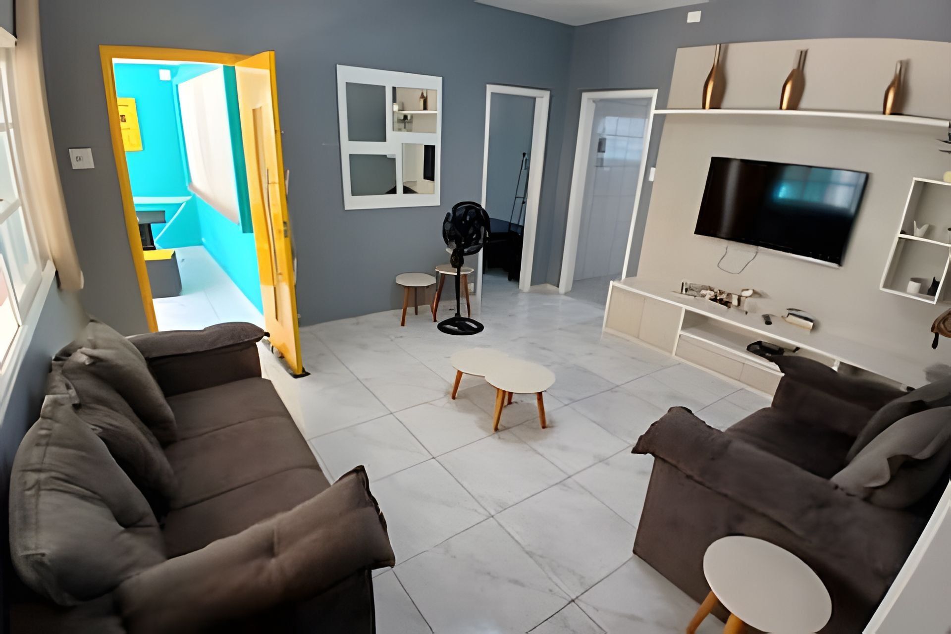 Una sala de estar con un sofá, un televisor y una mesita.
