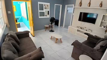 Una sala de estar con un sofá, un televisor y una mesita.
