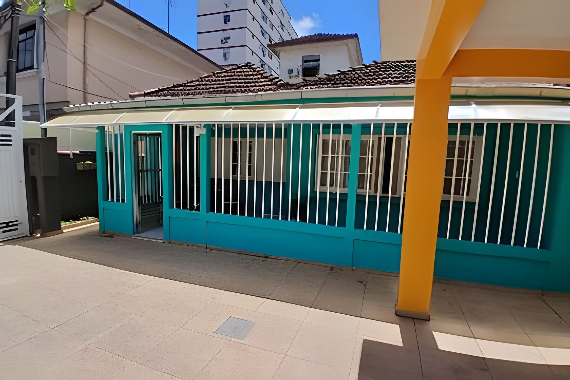 A building with a covered patio area, a gated entrance, and a tiled roof.