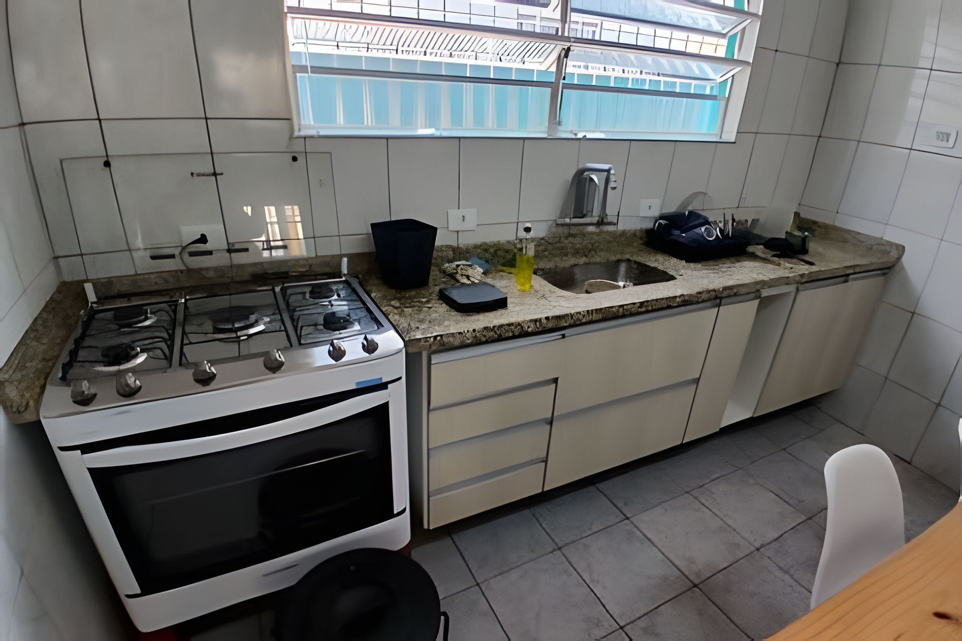 A kitchen with a gas stove, oven, sink, and window.